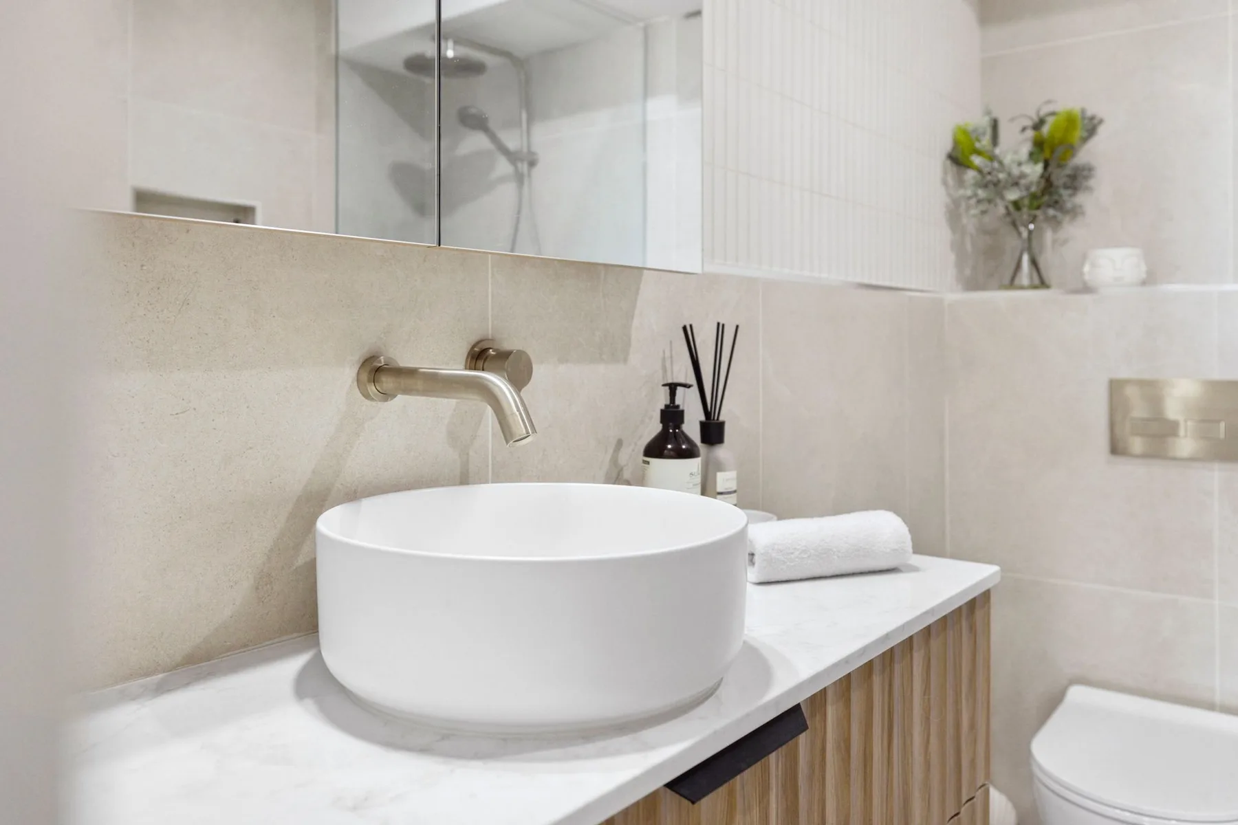 A bathroom vanity with a round vessel sink and wall-mounted faucet.