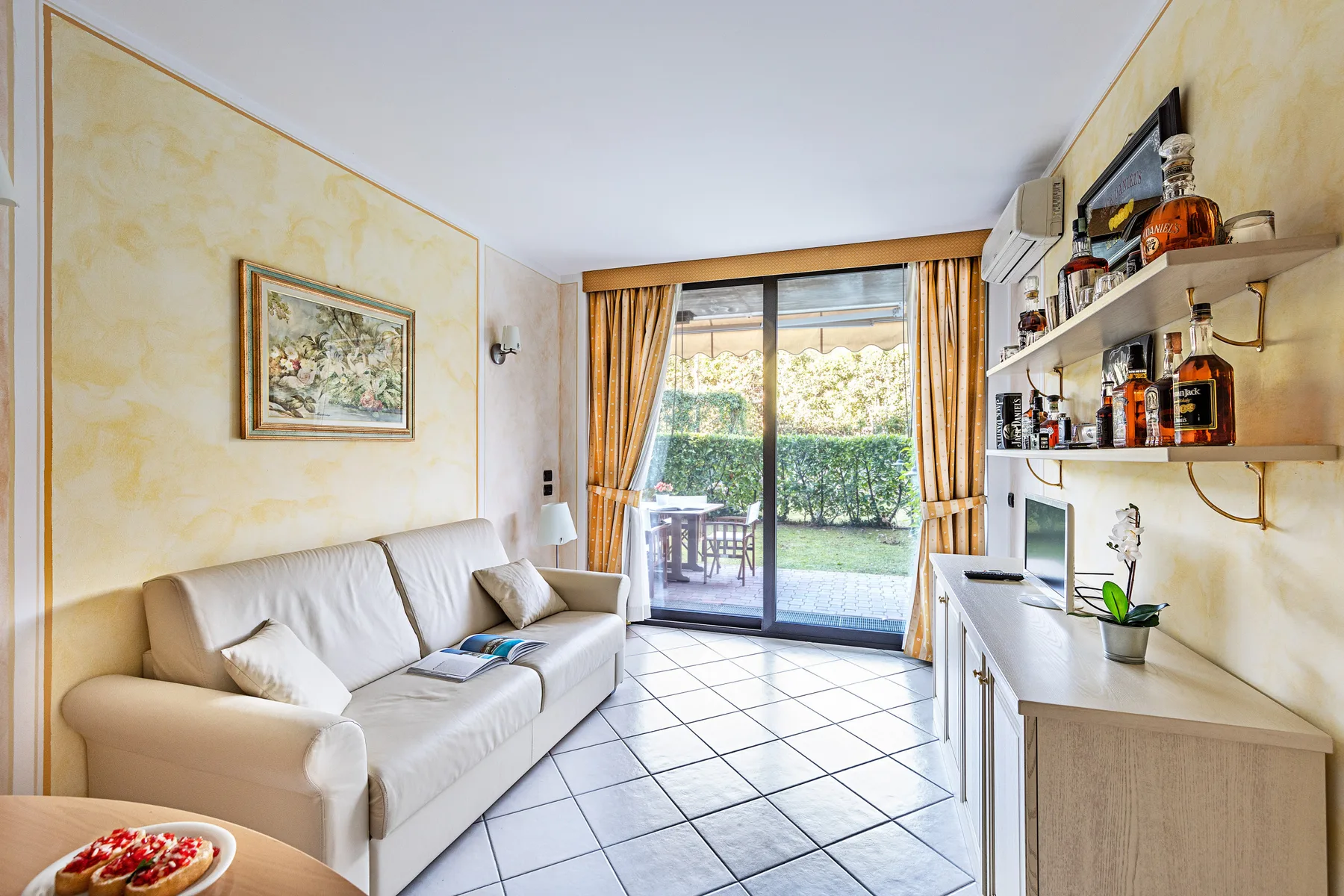 Una sala de estar con asientos junto a una puerta de vidrio que da a un jardín.
