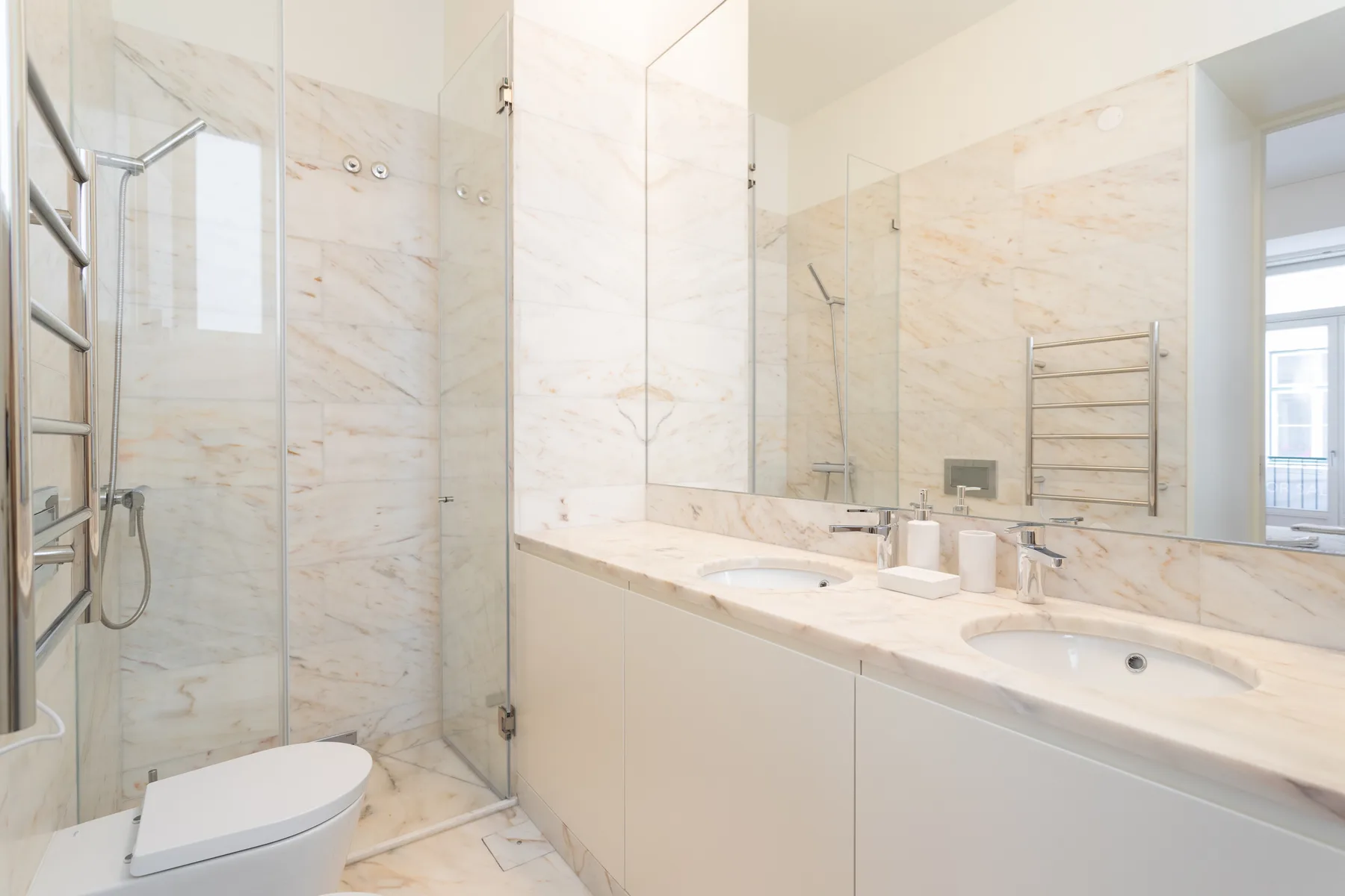 Un baño luminoso con una ducha de vidrio y un lavabo alargado.