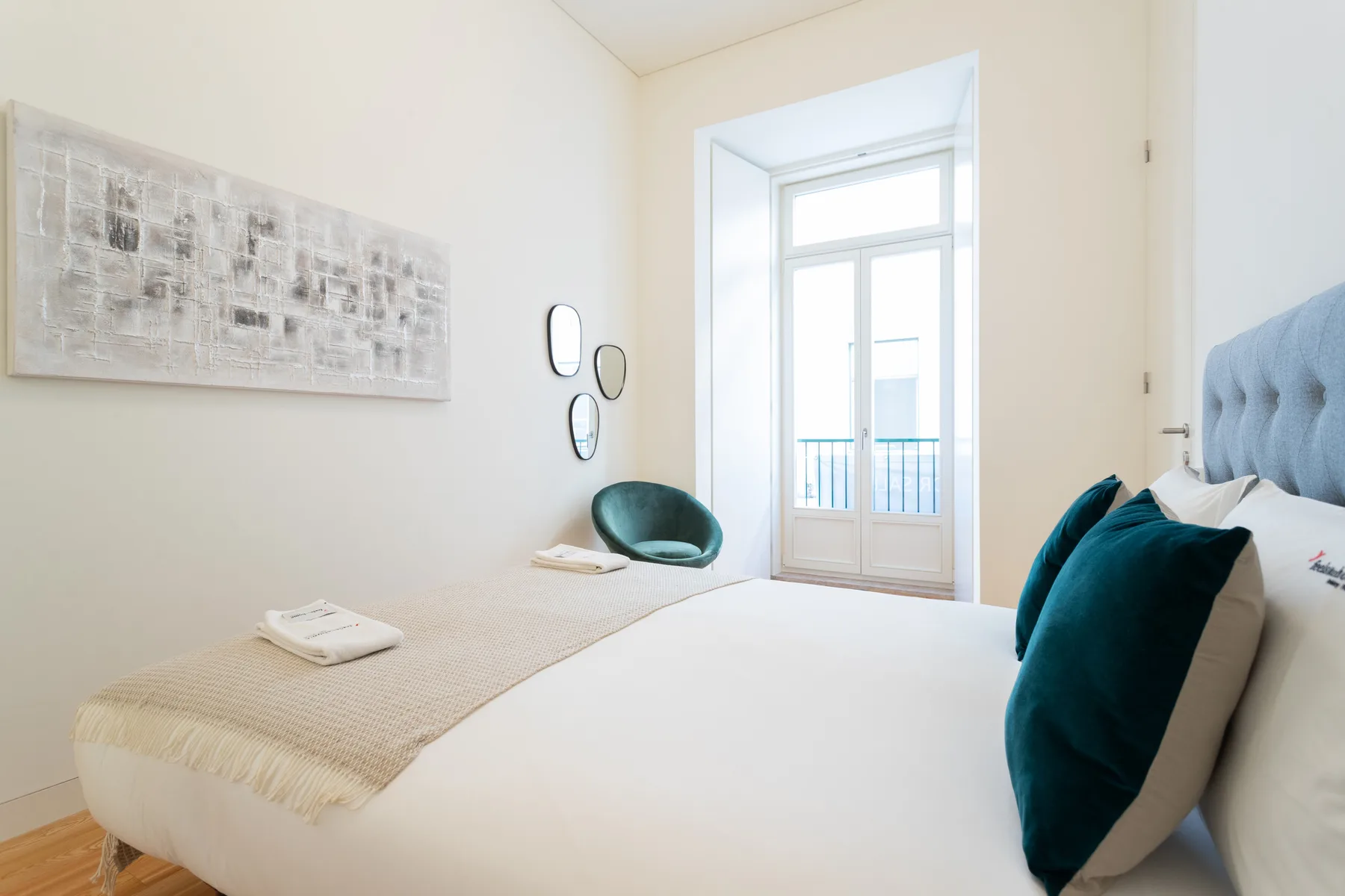 Un dormitorio luminoso con una cama y una puerta acristalada que da a un balcón.