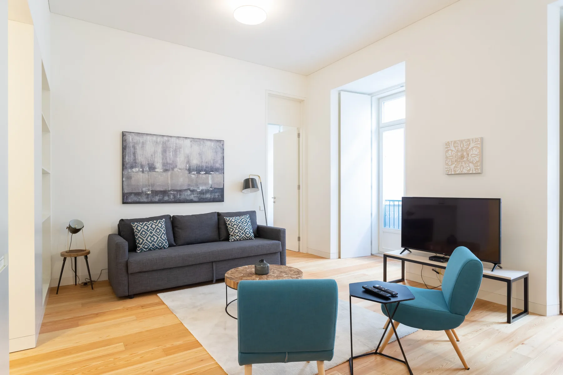 Sala de estar luminosa con sofá, televisor y asientos azules.