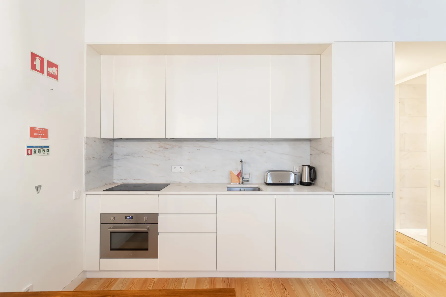Una cocina moderna con gabinetes blancos, una placa de cocina y una encimera.