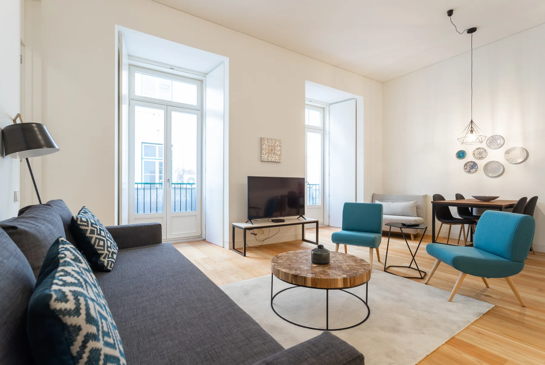 Una sala luminosa con asientos, un televisor y un comedor.