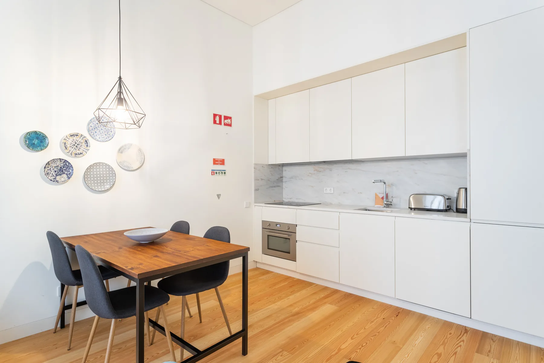 Comedor junto a una cocina moderna, con una mesa de madera y sillas.