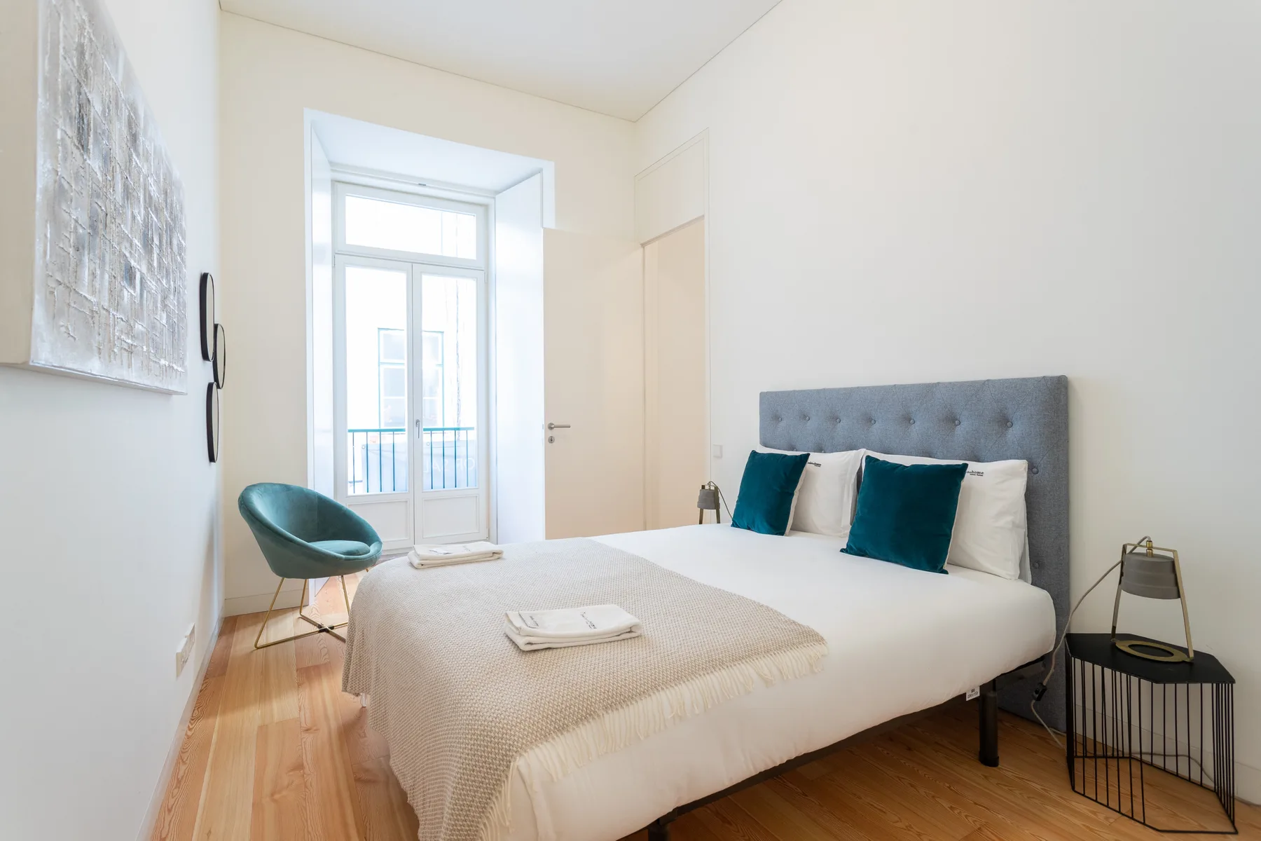 Dormitorio luminoso con una cama tendida y una ventana alta.