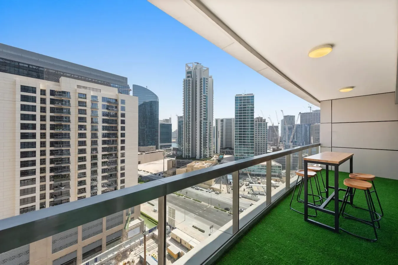 A balcony with seating overlooks a cluster of city high-rises.