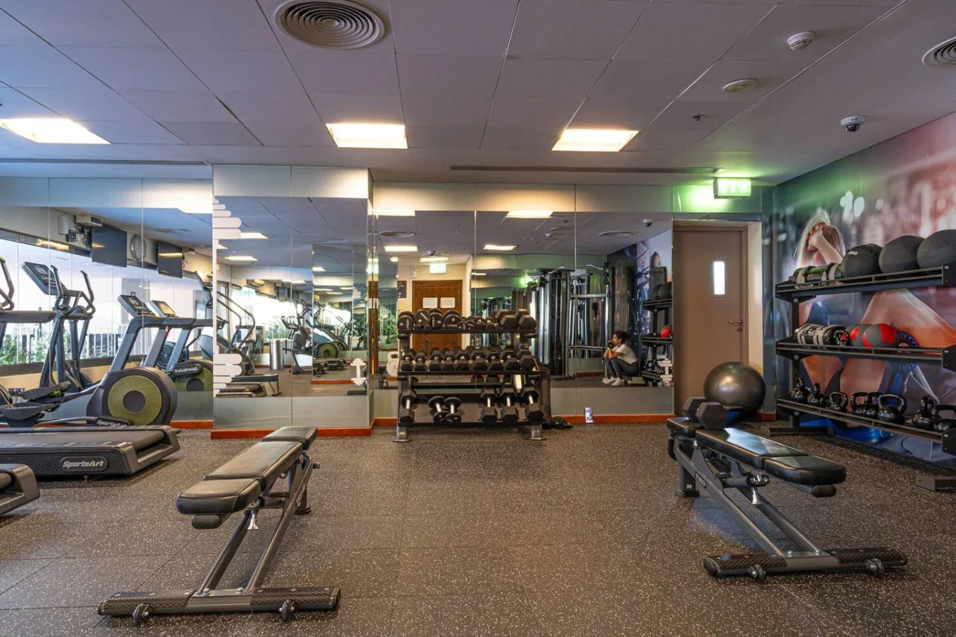 A gym with exercise equipment, weight racks, and mirrored walls.