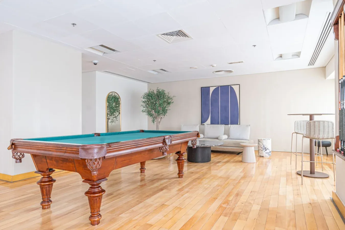A bright lounge with a wooden pool table and seating along the back wall.