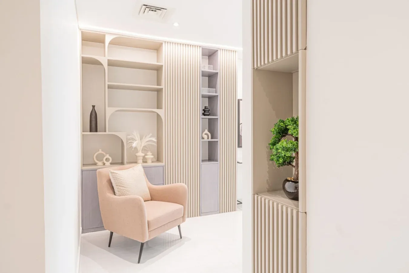 A bright interior seating nook with a pale armchair and built-in shelving.