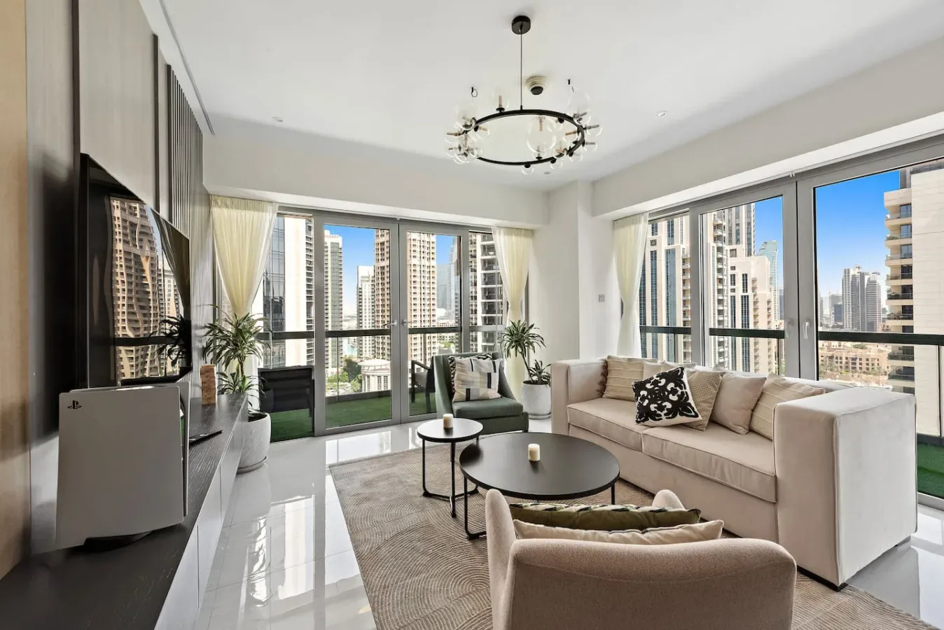 A bright living room with seating arranged beside large windows overlooking city buildings.