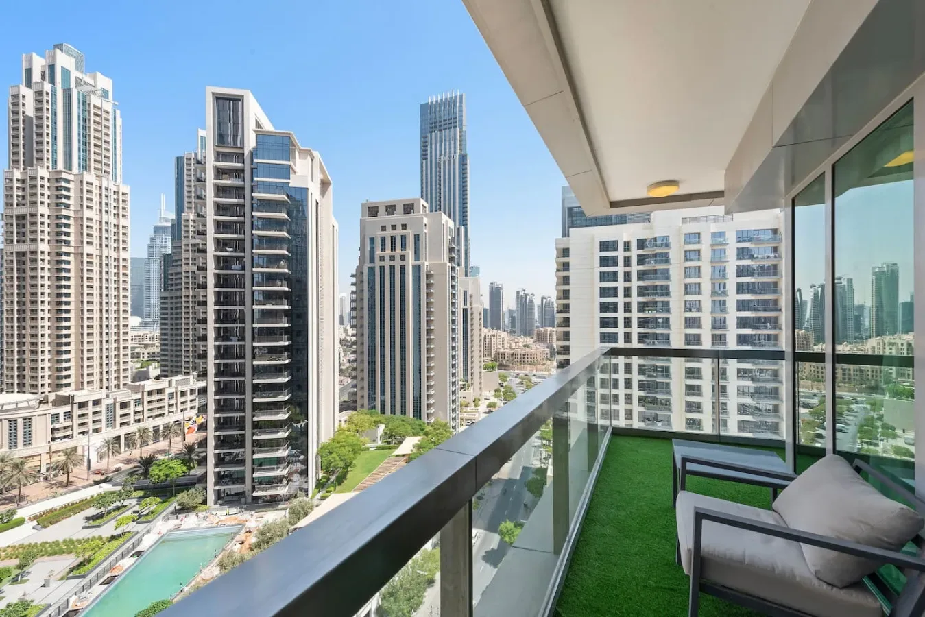 A balcony with seating overlooks a cluster of modern high-rise buildings.