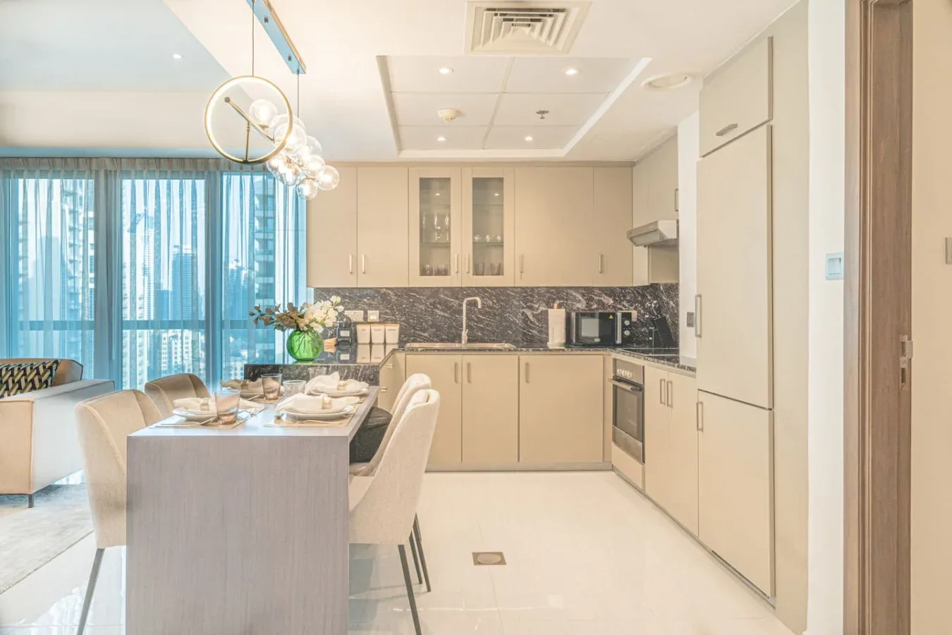 A bright kitchen and dining area with pale cabinetry and a table beside large windows.