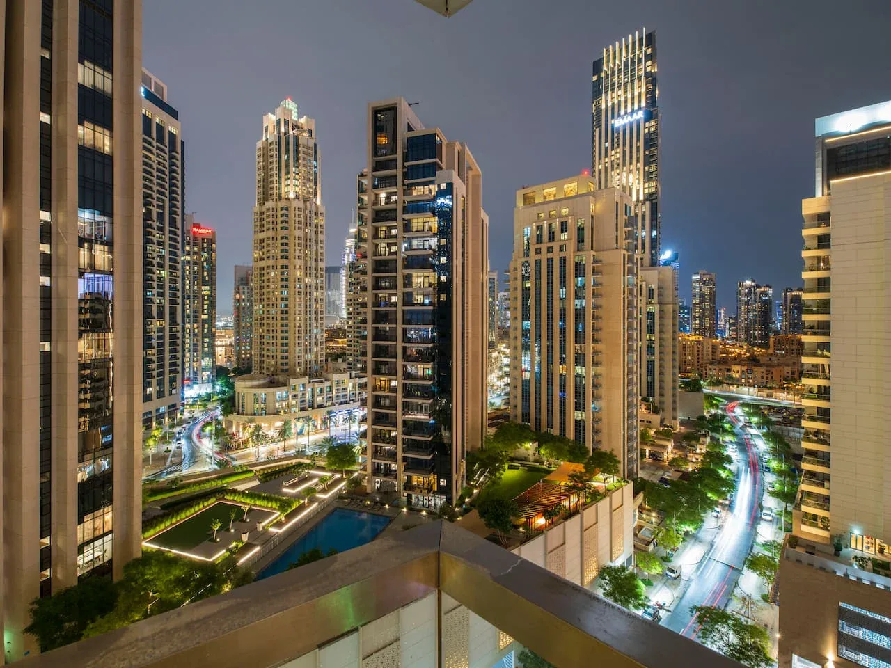 A nighttime cityscape shows illuminated high-rise buildings and busy roads.