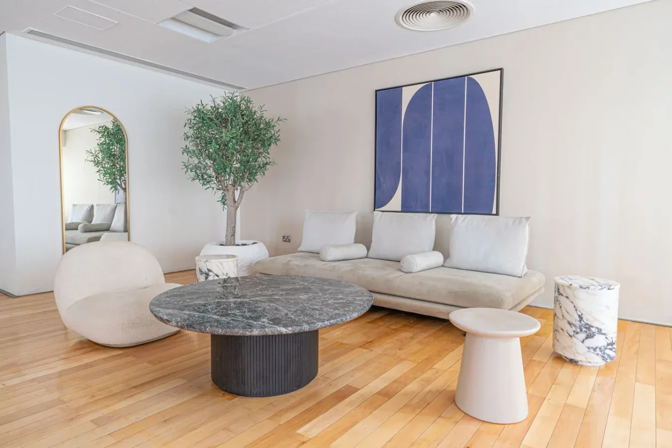 A bright living room with seating, a round coffee table, and abstract wall art.