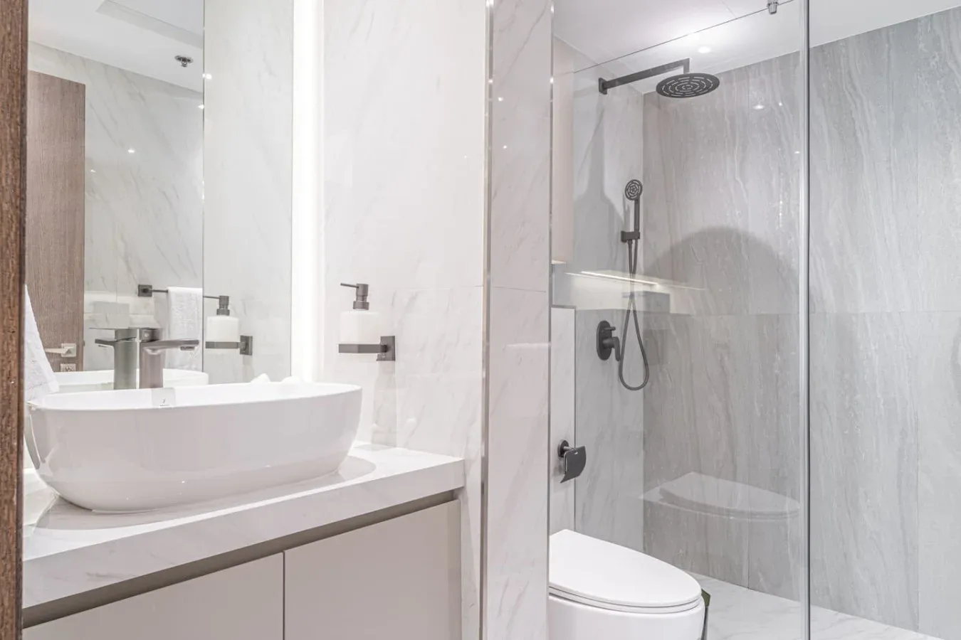 A bright bathroom with a sink, toilet, and glass-enclosed shower.
