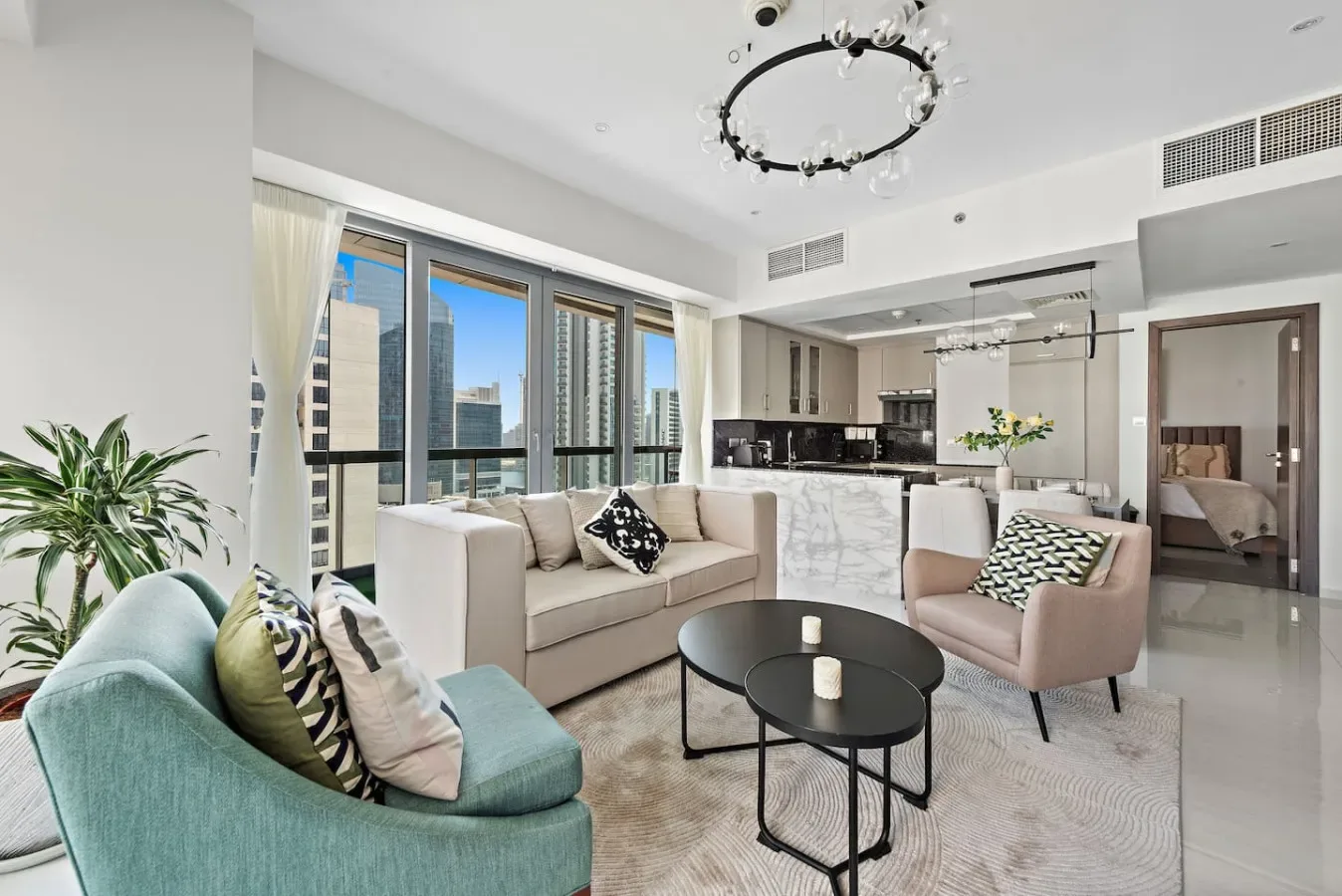 A bright living room with seating arranged around a black coffee table and large windows.