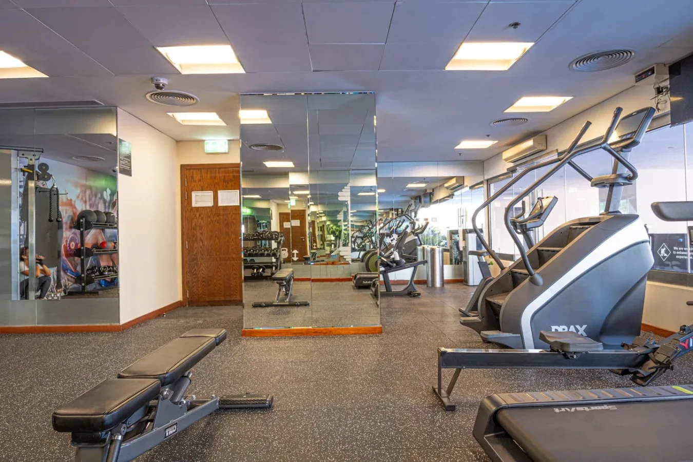 A gym with exercise machines and a mirrored wall.
