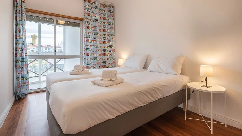 Un dormitorio luminoso con una cama grande junto a una ventana.