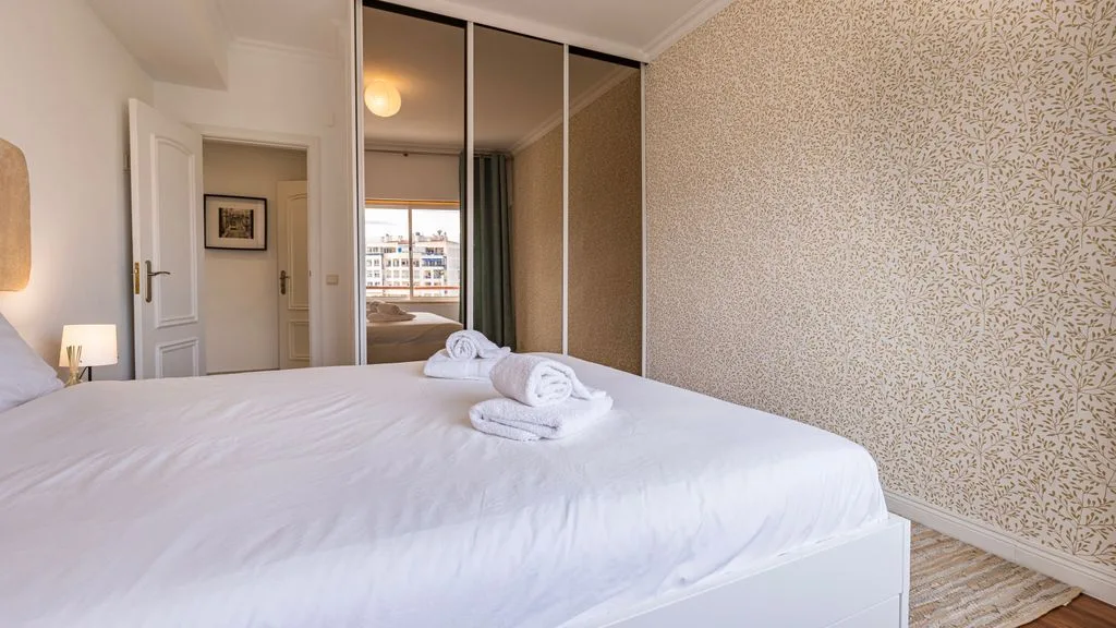 Un dormitorio con una cama bien tendida y toallas dobladas.