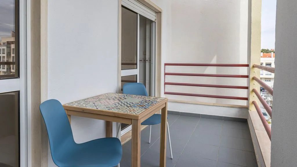 Un balcón con una mesa de azulejos y asientos azules.