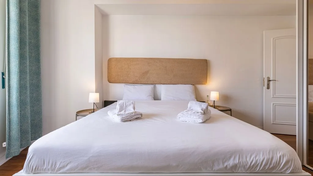 Un dormitorio luminoso con una cama bien hecha y lámparas de noche.