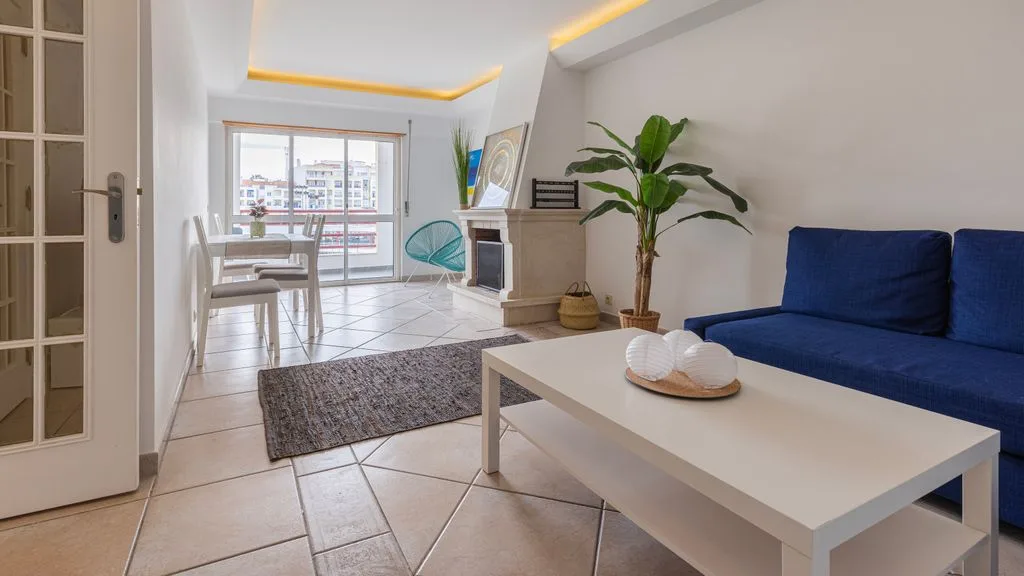 Una sala luminosa con asientos, una mesa de centro y una ventana grande.