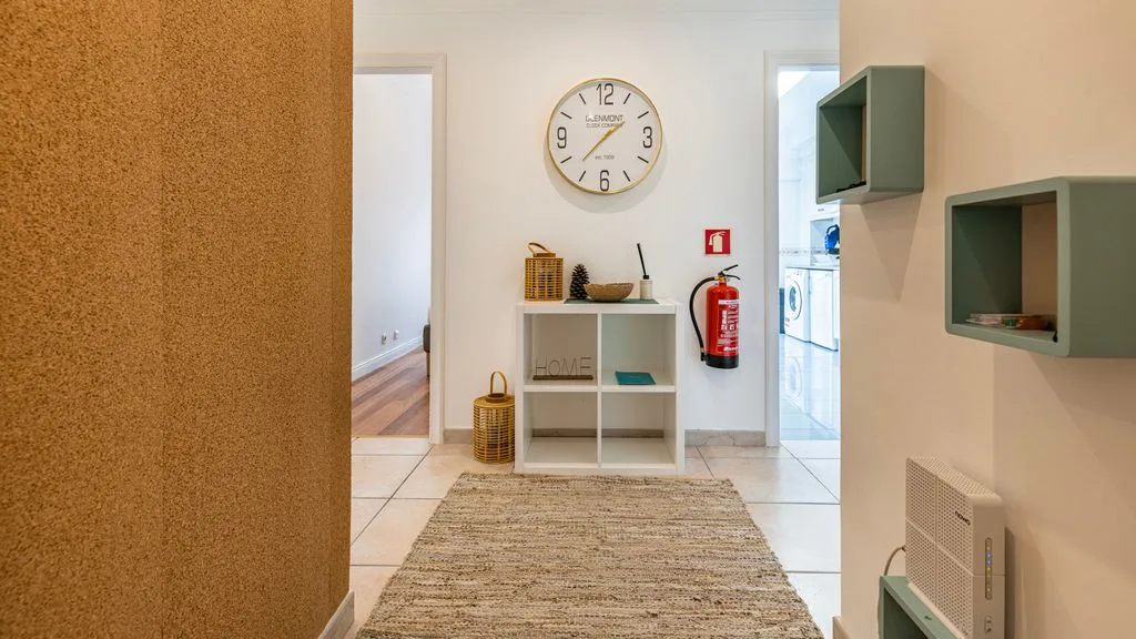 Un pasillo con una alfombra tejida y un reloj de pared.