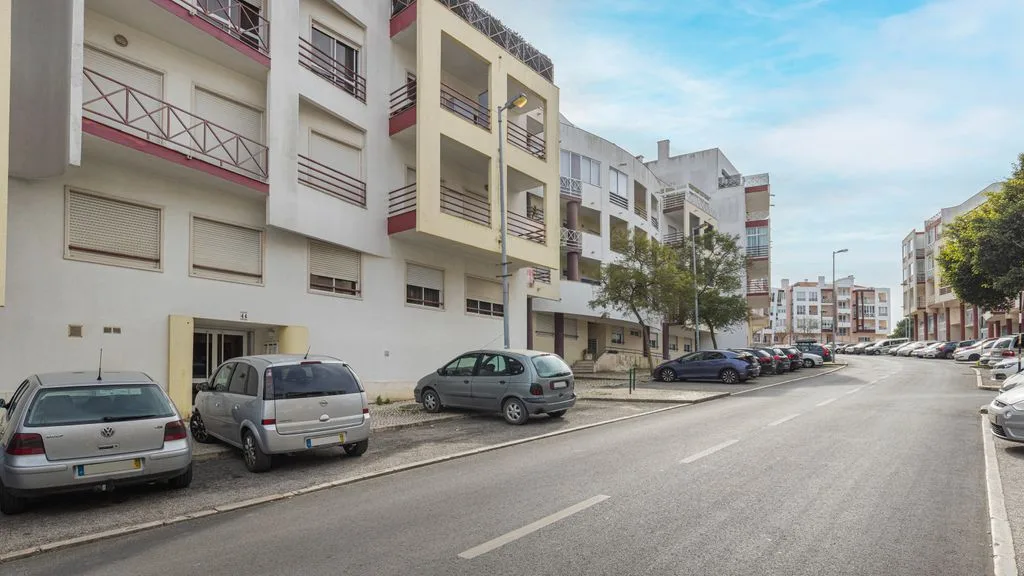 Una calle residencial tranquila con edificios de apartamentos y coches aparcados.