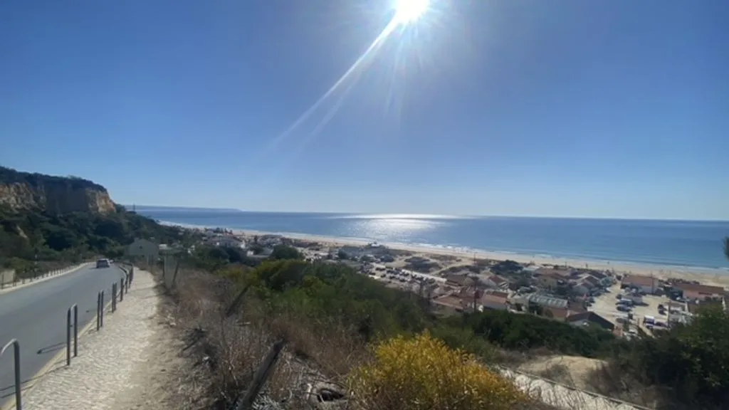 Un pueblo costero y una playa se extienden junto a la costa bajo un cielo despejado.