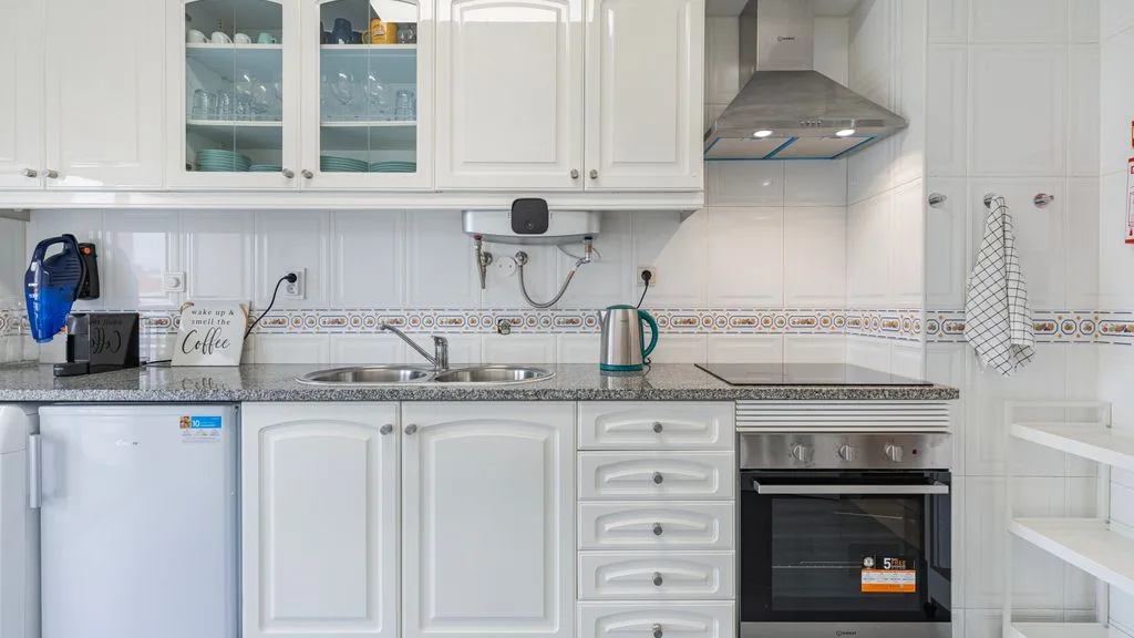 Una cocina luminosa con armarios blancos, encimera y electrodomésticos integrados.