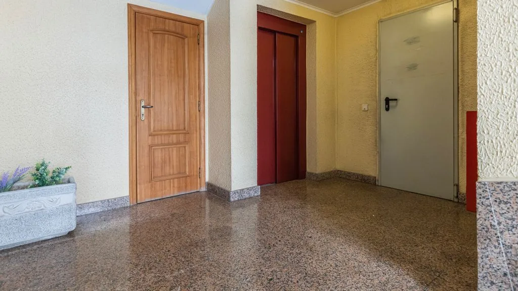 Un pasillo interior con varias puertas y un suelo pulido.