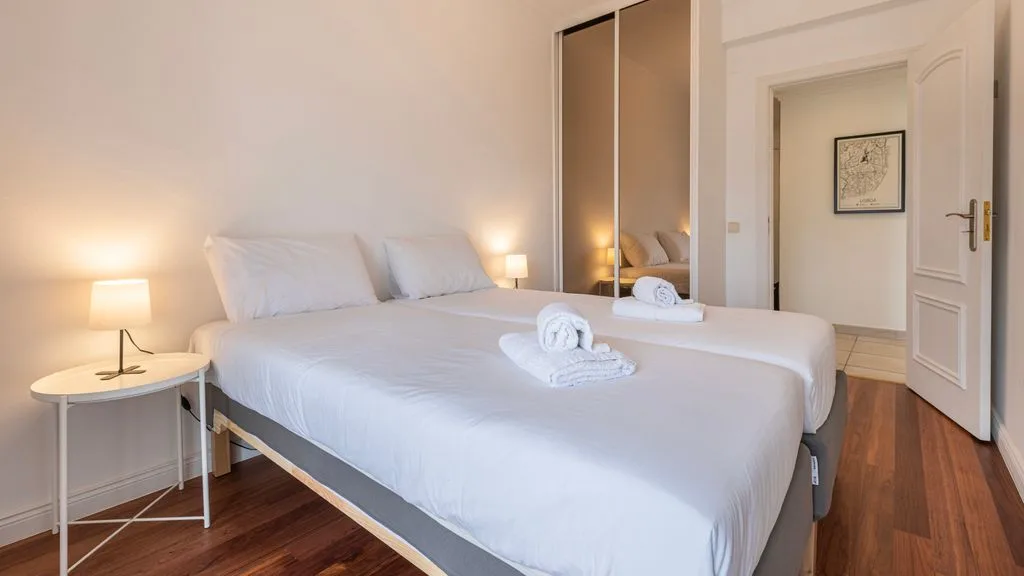 Un dormitorio luminoso con una cama tendida y lámparas de noche.