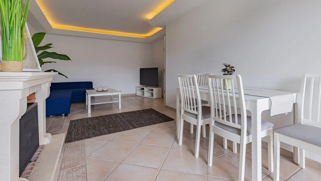 Una luminosa sala de estar y comedor con un sofá azul y una mesa blanca.