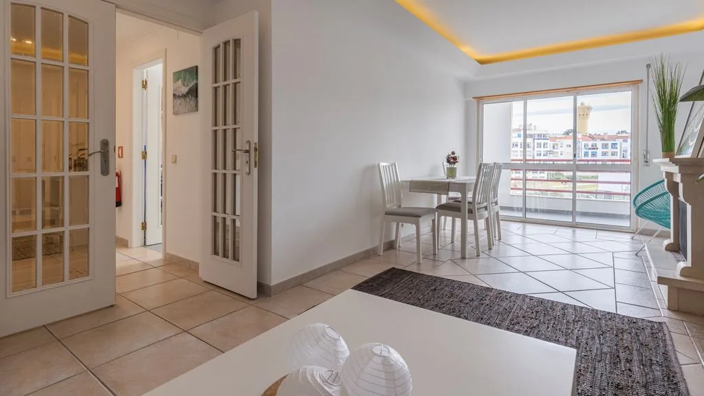 Un comedor luminoso con una mesa y grandes ventanas que dan a un balcón.
