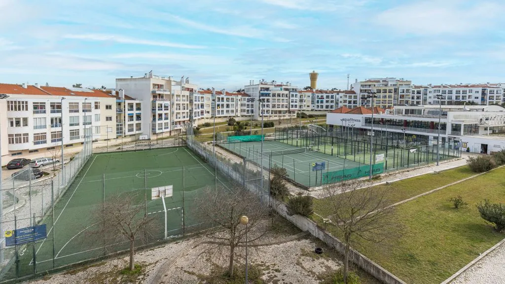 Vista de canchas deportivas cercadas y edificios de apartamentos alrededor.
