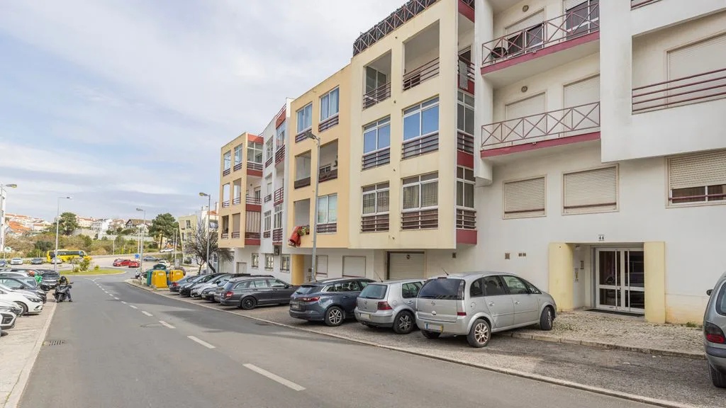 Una calle bordeada de edificios de apartamentos y coches estacionados.