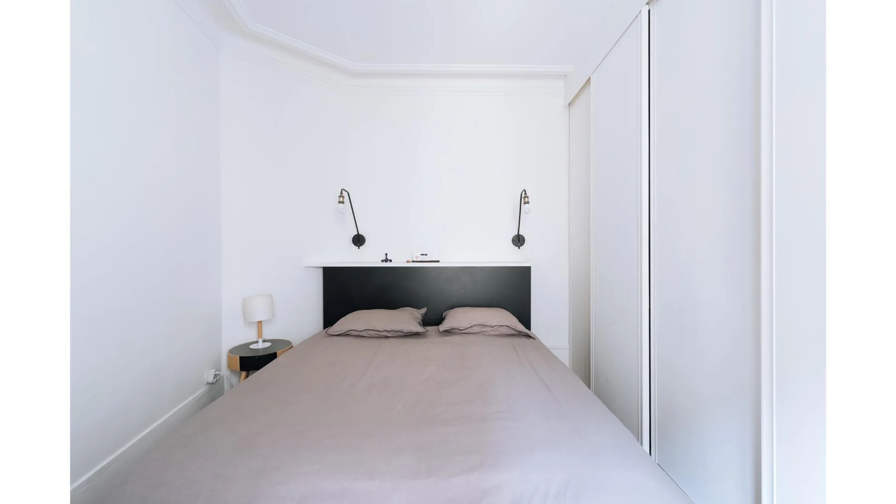 Un dormitorio con una cama y dos luces de pared.