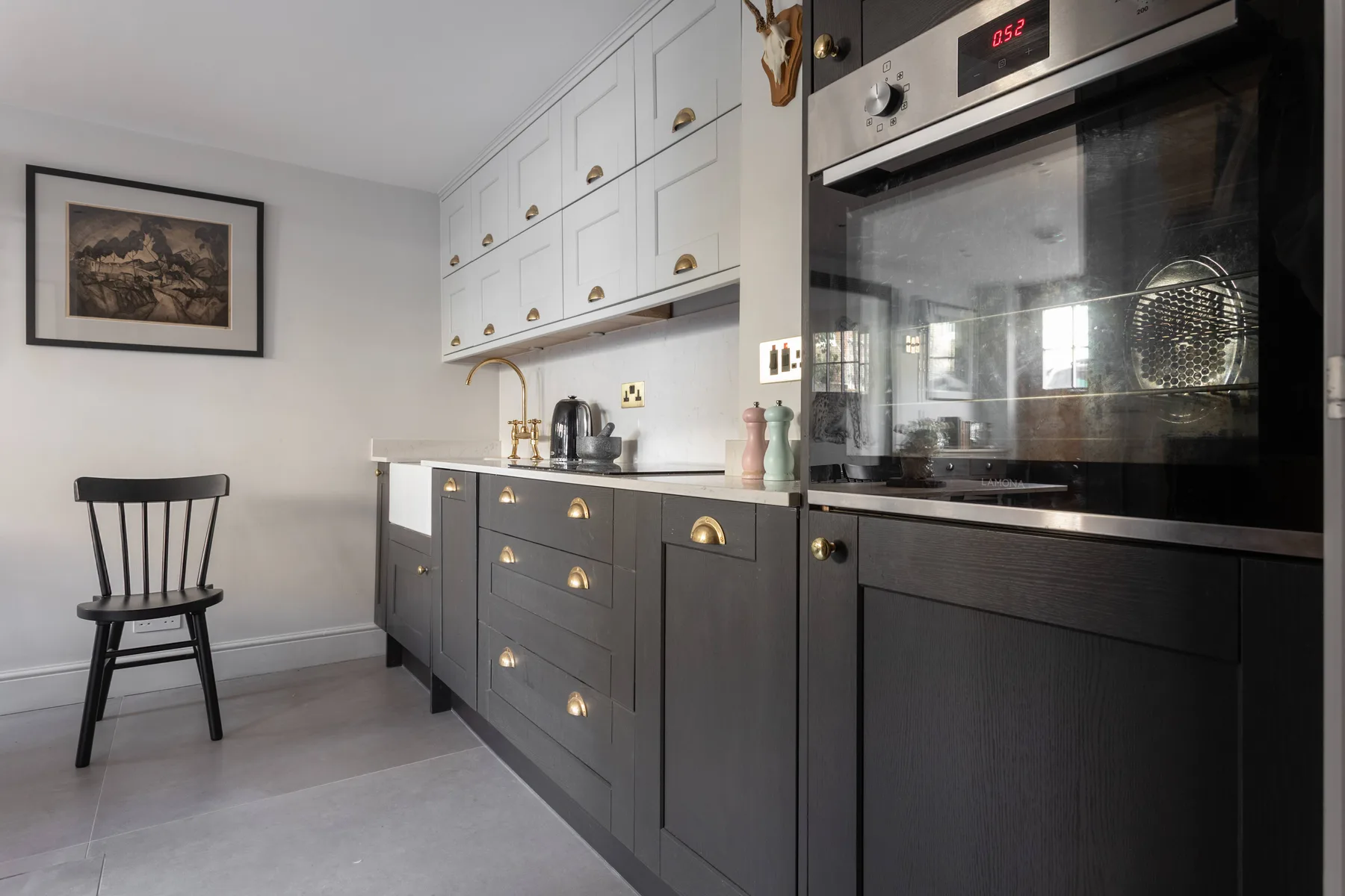 Una cocina moderna con gabinetes oscuros, gabinetes superiores blancos y un horno empotrado.