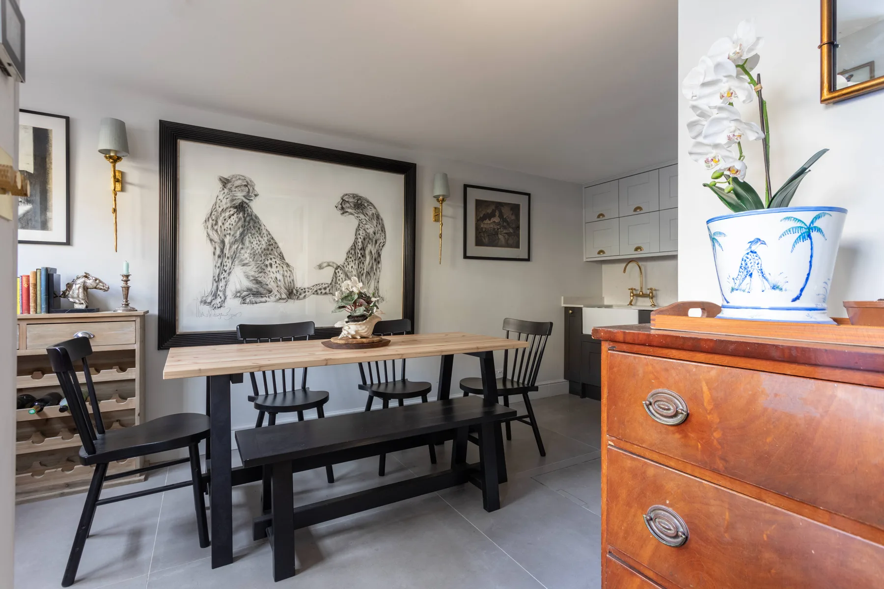 Comedor con una mesa larga de madera y bancos bajo obras enmarcadas.