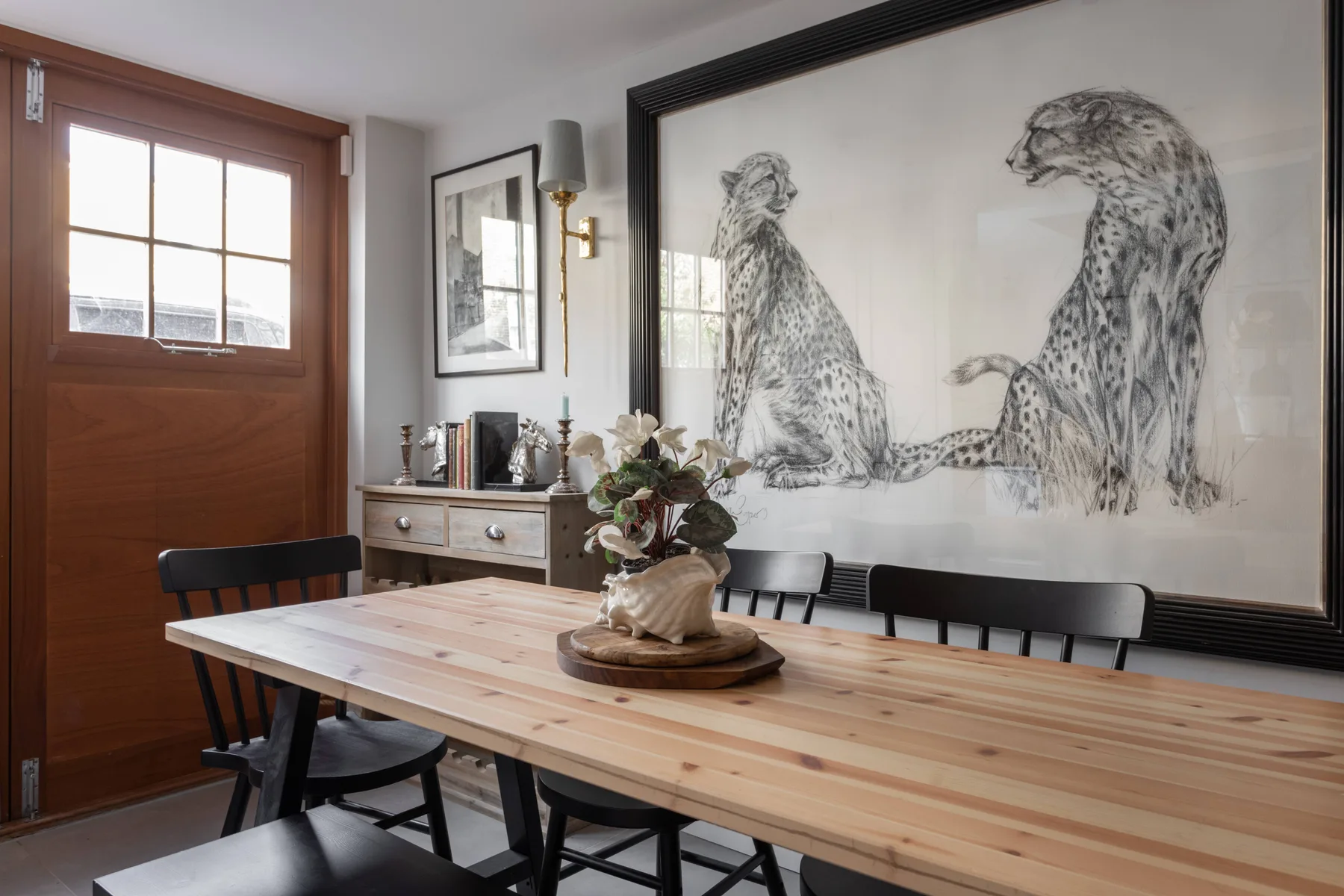 Un comedor con una mesa larga de madera y una gran obra de arte enmarcada.