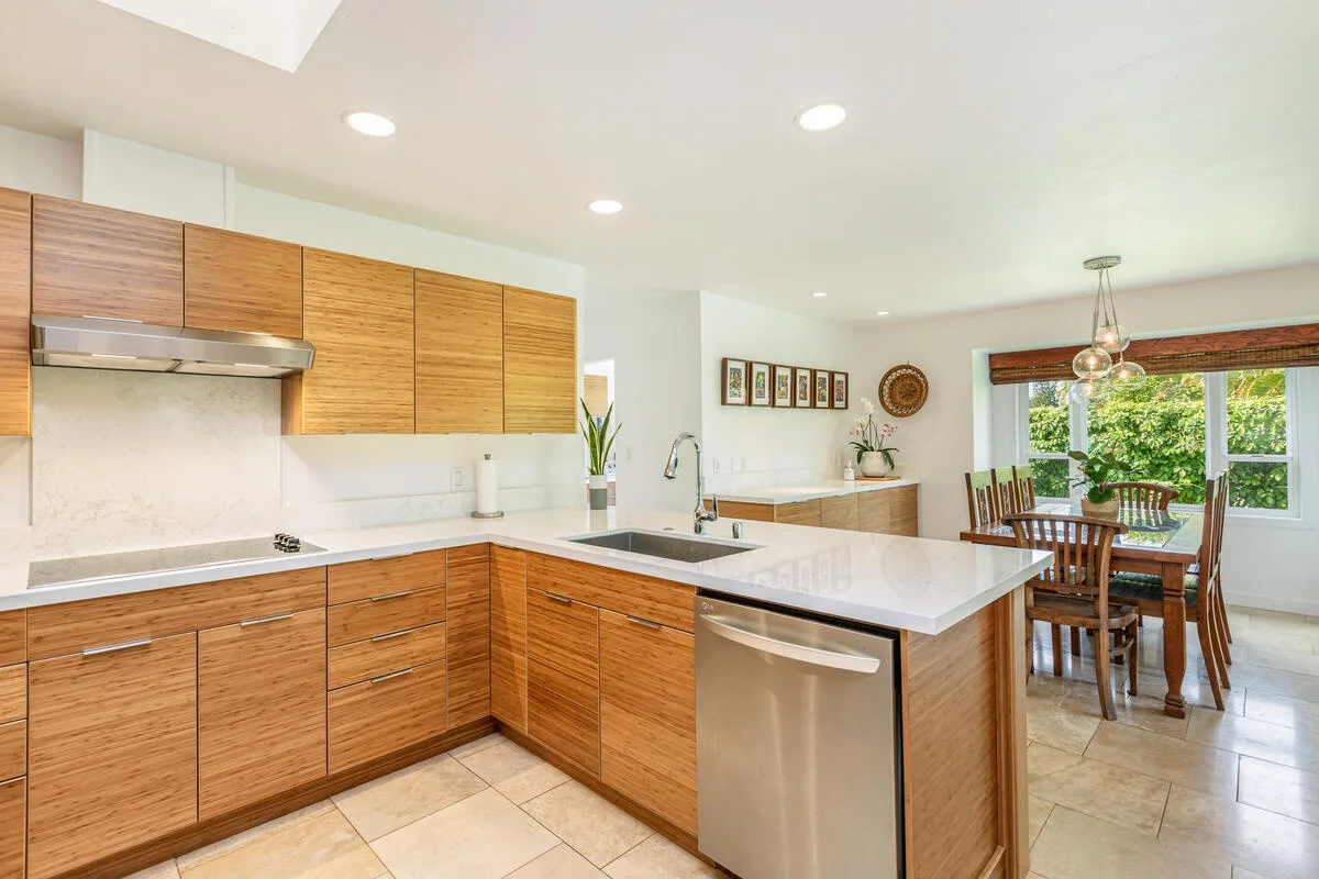 A bright kitchen with wood cabinetry opens onto a dining area.