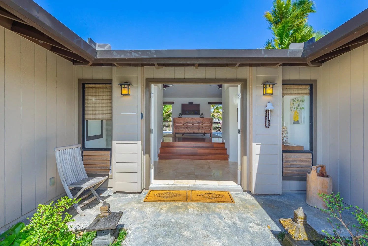 A courtyard entry opens toward a covered seating area, with planters along the walkway.