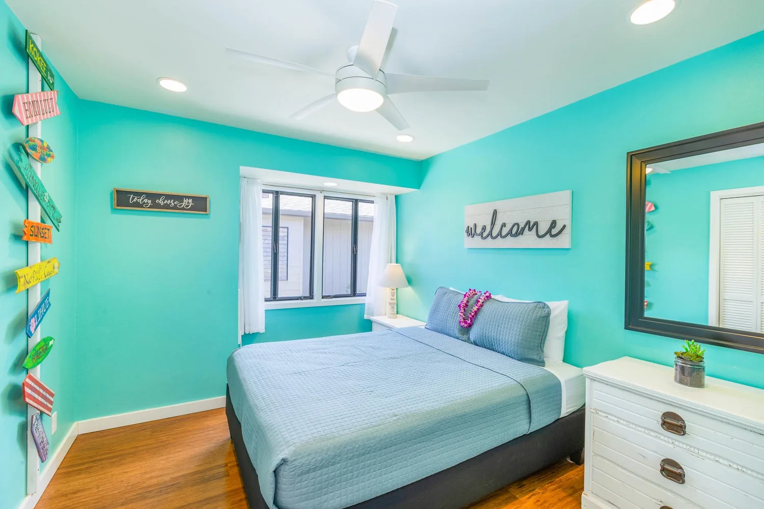 A bright bedroom with a bed, turquoise walls, and a window.