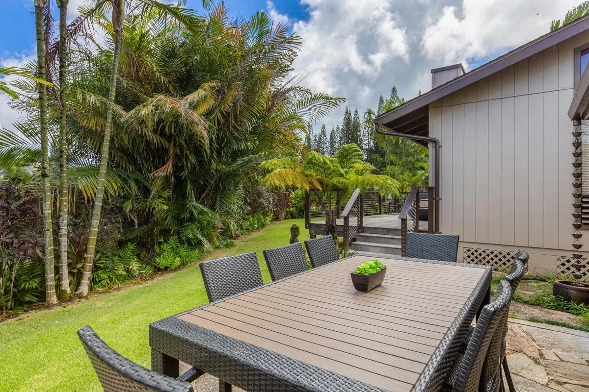 An outdoor dining area with a table and chairs beside a garden.