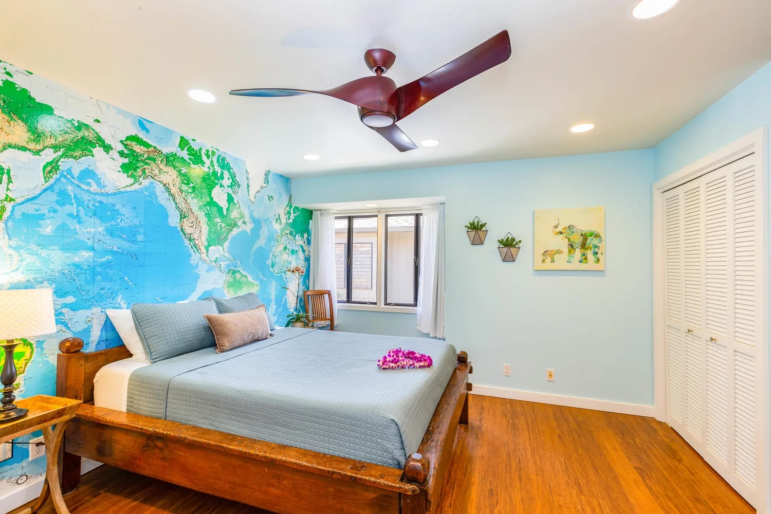 A bedroom with a wooden bed and a colorful world map mural.