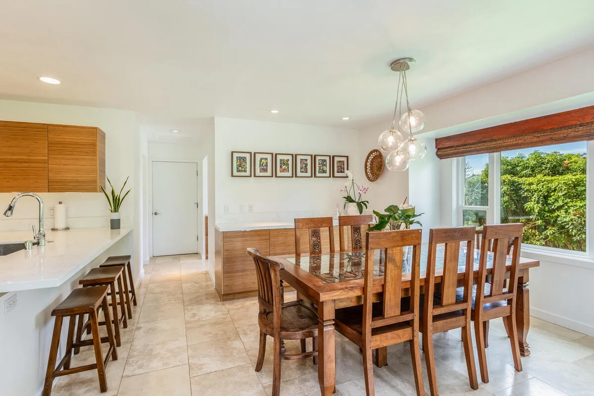 A bright dining area with a wooden table and chairs beside a large window.