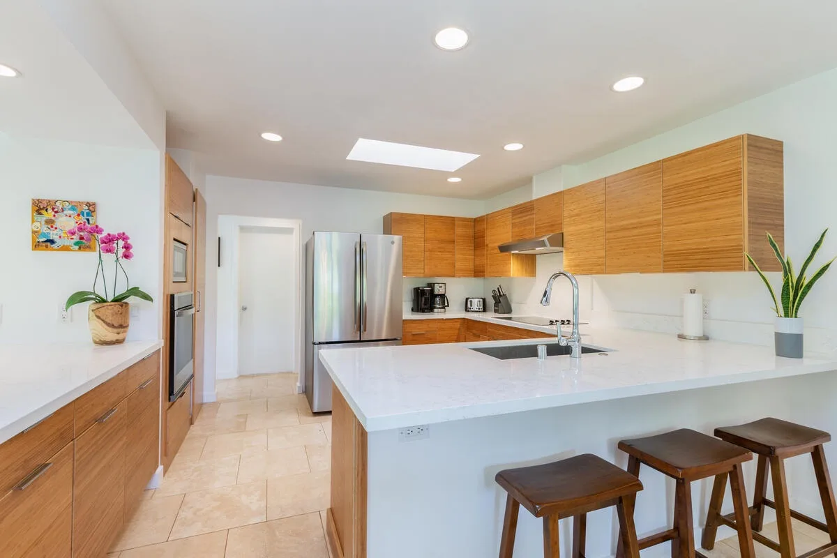Una cocina moderna con gabinetes de madera, electrodomésticos de acero inoxidable y una isla central.