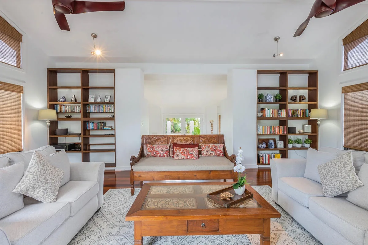 A bright living room with seating, bookshelves, and a wooden coffee table.