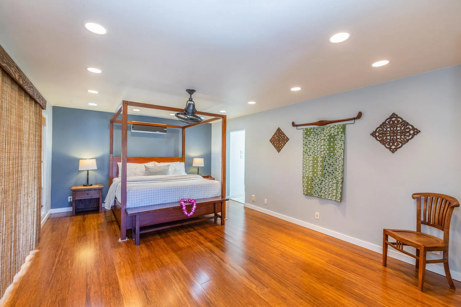 A bedroom with a four-poster bed, ceiling fan, and wood flooring.