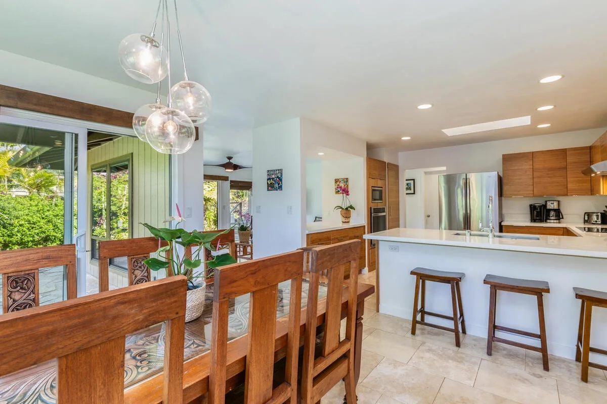 A bright kitchen and dining area features a wooden dining table beside a white island.